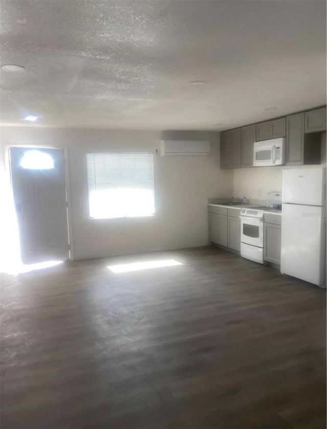 kitchen with a wall mounted AC, gray cabinetry, a textured ceiling, white appliances, and dark hardwood / wood-style flooring