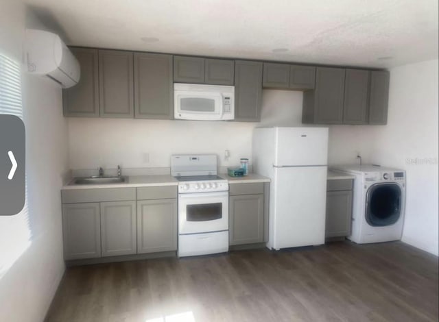 kitchen with white appliances, washer / clothes dryer, sink, a wall mounted air conditioner, and dark wood-type flooring