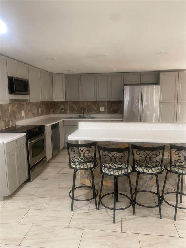 kitchen with stainless steel appliances, decorative backsplash, sink, and gray cabinets