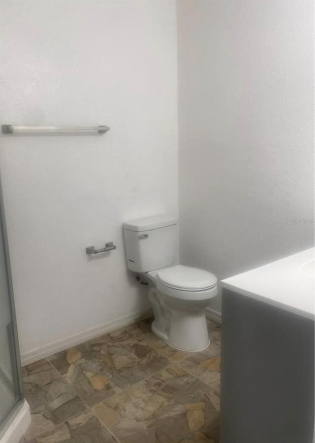 bathroom with vanity, toilet, and a shower with shower door