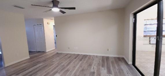 spare room with baseboards, ceiling fan, wood finished floors, and visible vents