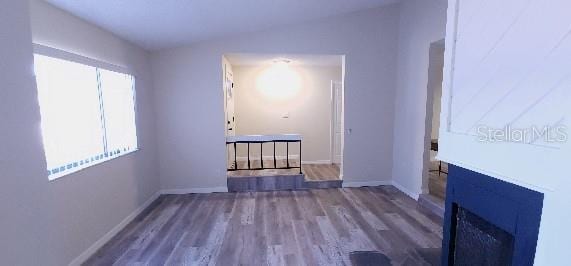 unfurnished room with baseboards, wood finished floors, and a fireplace