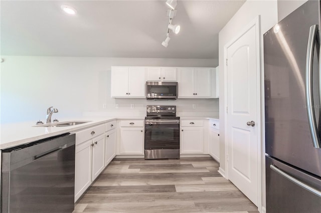 kitchen with white cabinetry, appliances with stainless steel finishes, sink, and light wood-type flooring