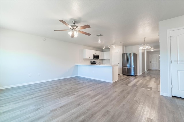 unfurnished living room featuring a textured ceiling, light hardwood / wood-style flooring, and ceiling fan with notable chandelier