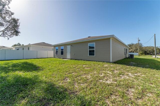 back of house with central AC and a yard