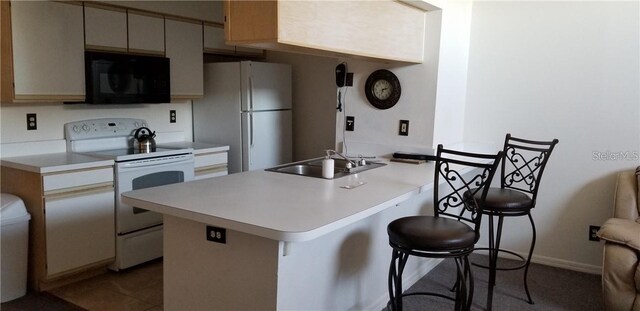 2456 Sweetwater Club Cir Unit 20, Kissimmee, FL 34746 - kitchen featuring white appliances, a breakfast bar, light countertops, and a sink