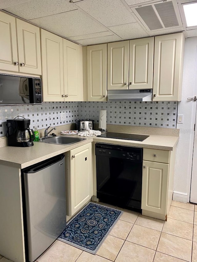 kitchen featuring black appliances, decorative backsplash, light tile patterned floors, and cream cabinetry