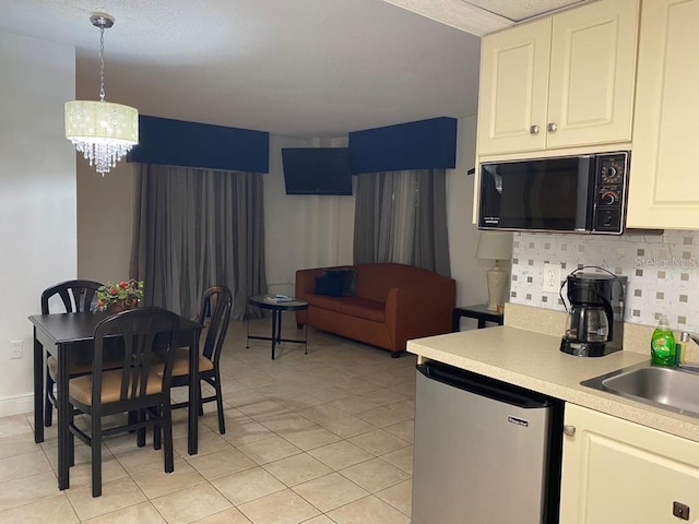 6165 Carrier Dr Unit 2113, Orlando, FL 32819 - kitchen featuring black microwave, backsplash, a chandelier, refrigerator, and a sink