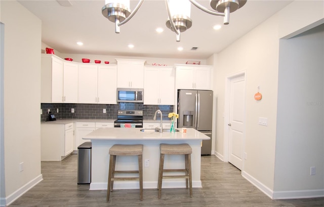 kitchen with white cabinets, a kitchen island with sink, stainless steel appliances, and wood-type flooring