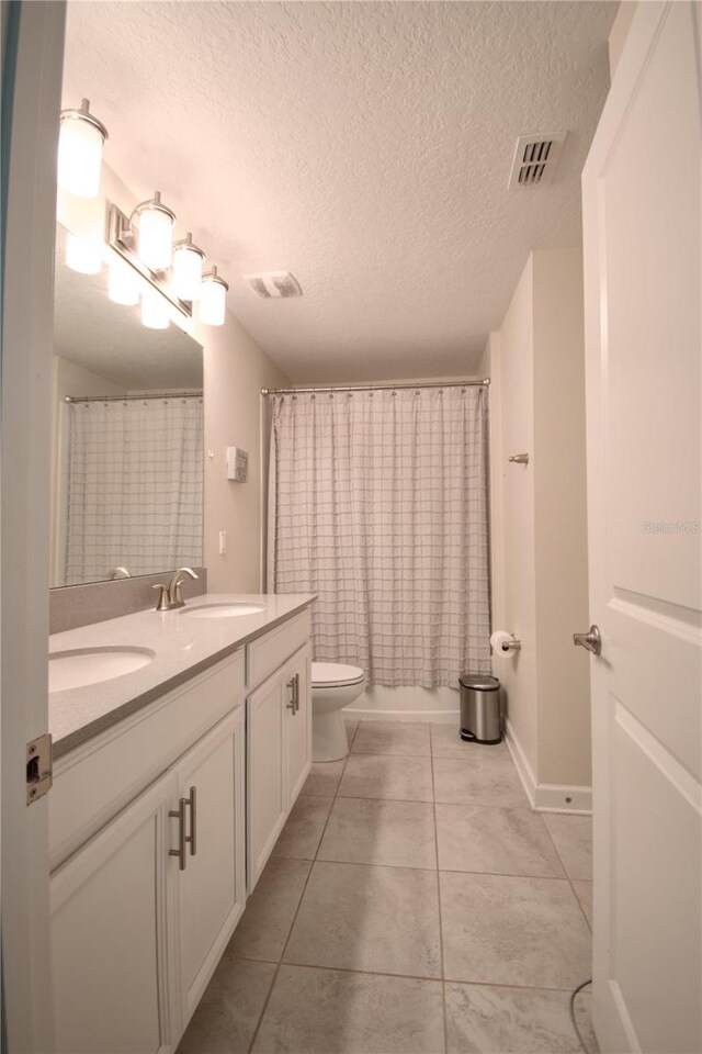 bathroom featuring vanity, toilet, a textured ceiling, and tile patterned flooring