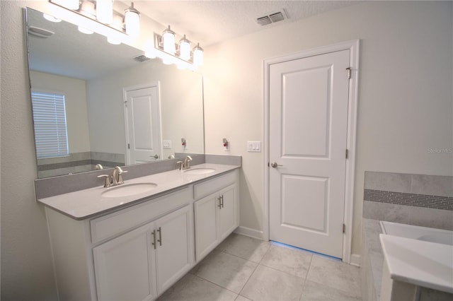 bathroom featuring vanity, a textured ceiling, tile patterned floors, and a bath