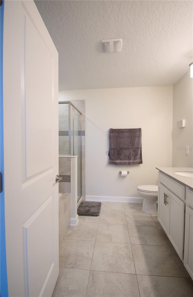 bathroom featuring toilet, tile patterned flooring, vanity, a textured ceiling, and walk in shower