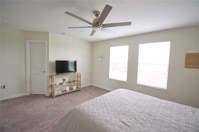 bedroom with ceiling fan, light carpet, and a textured ceiling