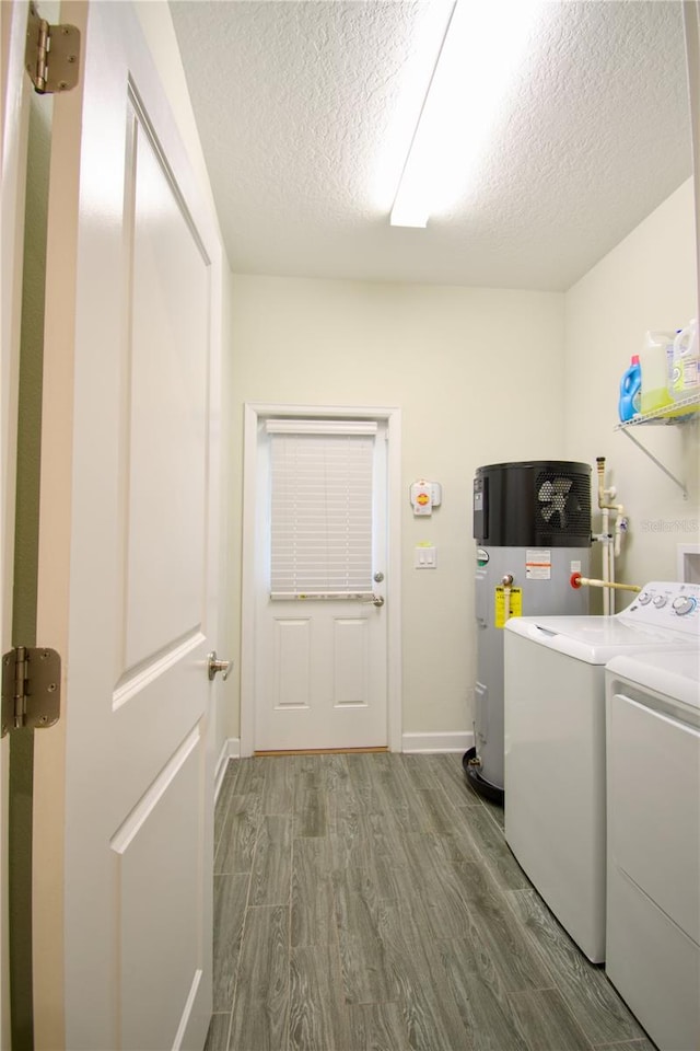 laundry area featuring a textured ceiling, hardwood / wood-style flooring, separate washer and dryer, and heat pump water heater