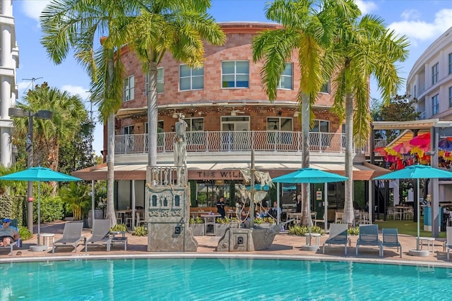 back of property featuring a patio area, a balcony, and a community pool