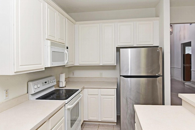 kitchen featuring white cabinetry, light tile patterned floors, and white appliances