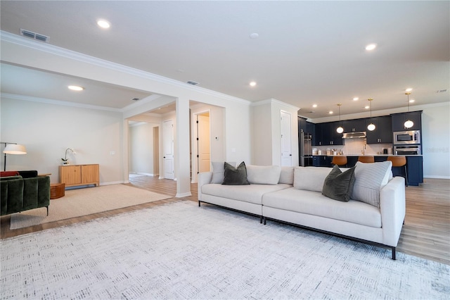 living room with crown molding and light hardwood / wood-style floors