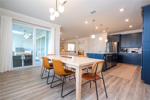 dining space featuring light hardwood / wood-style floors, crown molding, and an inviting chandelier