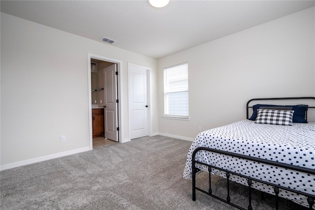 bedroom with ensuite bathroom and light colored carpet