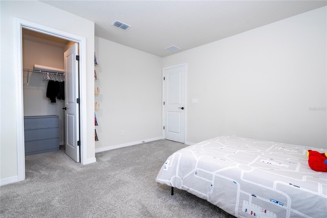 carpeted bedroom featuring a closet and a walk in closet