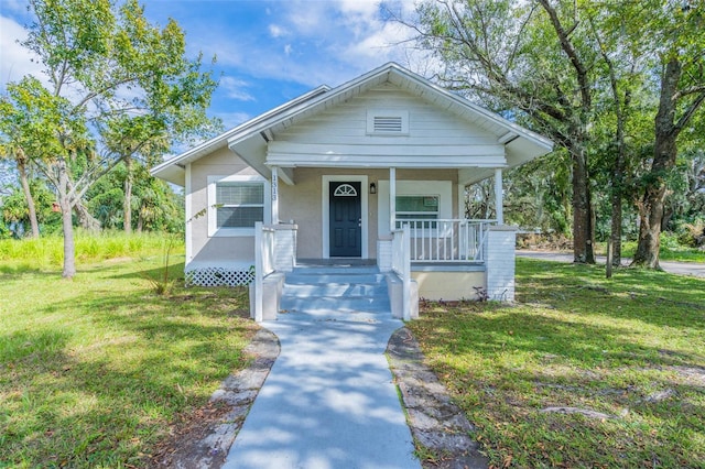 bungalow-style home featuring covered porch and a front yard