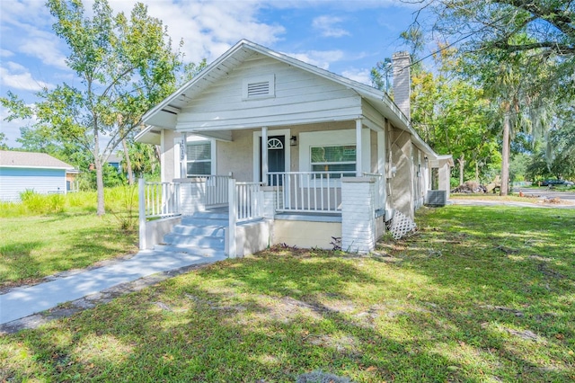 bungalow with a porch, a front yard, and central AC