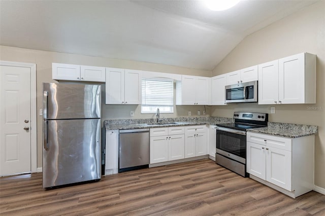 kitchen featuring vaulted ceiling, white cabinets, sink, dark hardwood / wood-style floors, and appliances with stainless steel finishes