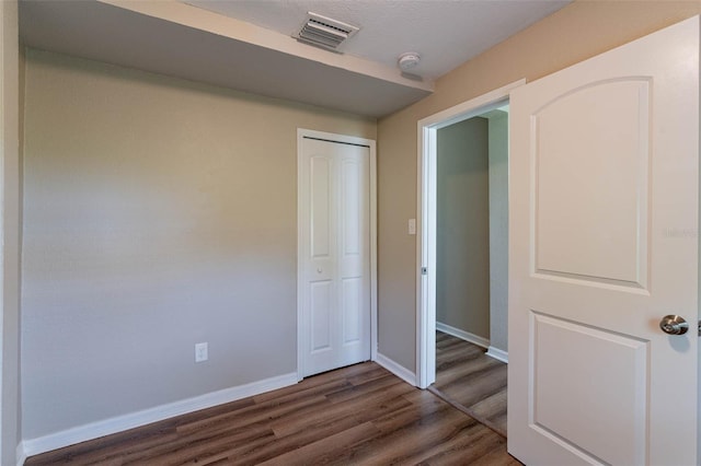 unfurnished bedroom featuring a closet and dark hardwood / wood-style flooring