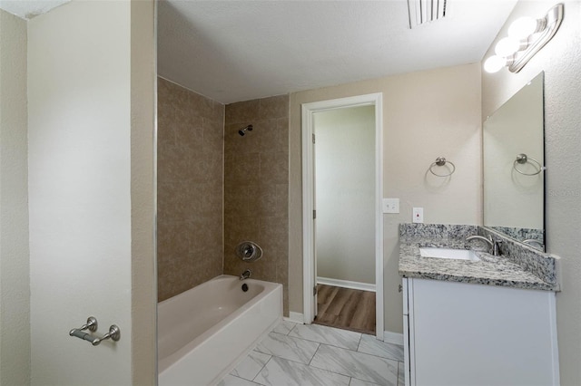 bathroom featuring vanity, a textured ceiling, and tiled shower / bath combo