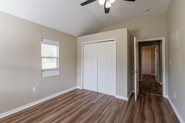 unfurnished bedroom with dark hardwood / wood-style flooring, lofted ceiling, ceiling fan, and a closet