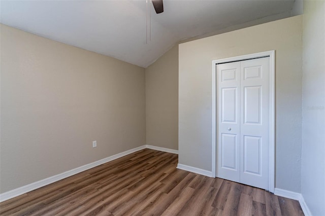 unfurnished bedroom with dark wood-type flooring, ceiling fan, a closet, and lofted ceiling