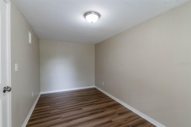 unfurnished room featuring dark wood-type flooring and a textured ceiling