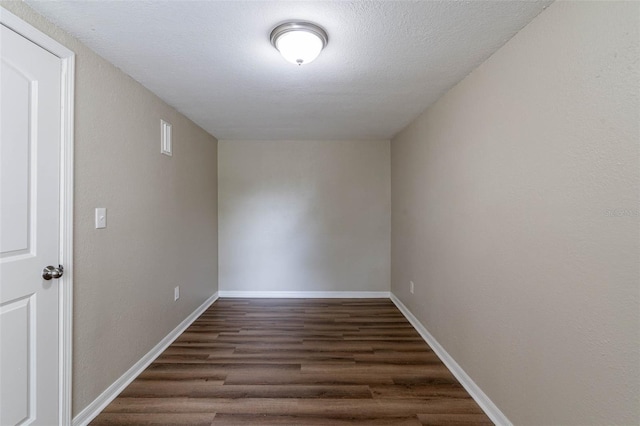 empty room with dark wood-type flooring and a textured ceiling