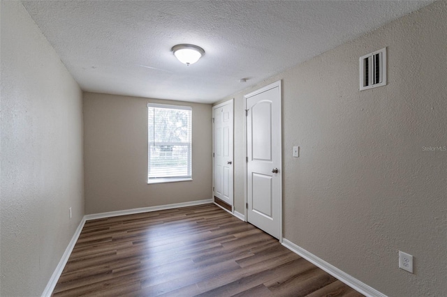 spare room featuring a textured ceiling and dark hardwood / wood-style floors