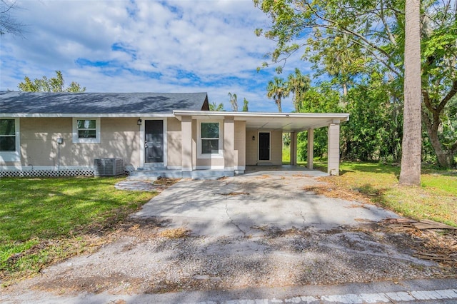 ranch-style home featuring central air condition unit, a front lawn, and a carport