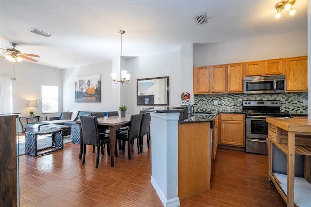 kitchen featuring decorative backsplash, appliances with stainless steel finishes, dark hardwood / wood-style floors, and hanging light fixtures