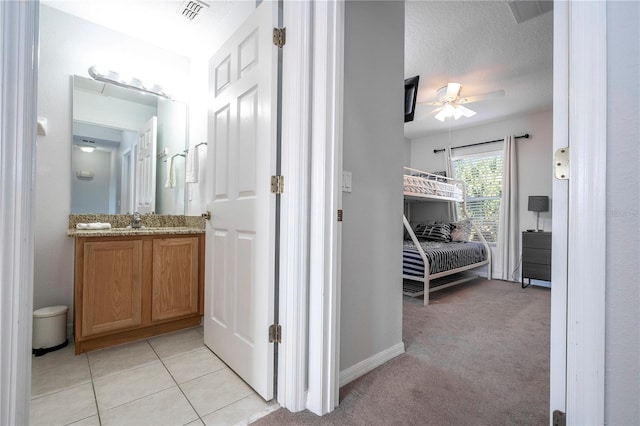 hall featuring a textured ceiling, light colored carpet, and sink