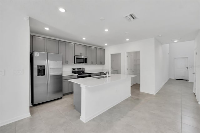 kitchen featuring gray cabinetry, stainless steel appliances, a kitchen island with sink, sink, and light tile patterned floors