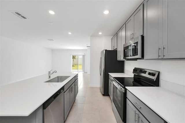 kitchen with light tile patterned flooring, stainless steel appliances, gray cabinetry, and sink