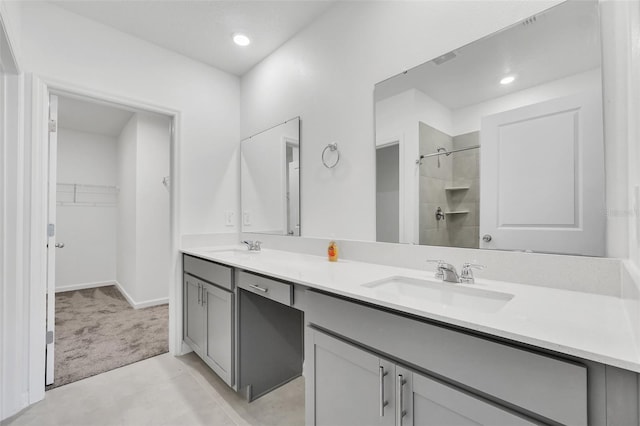 bathroom with tiled shower, vanity, and tile patterned flooring