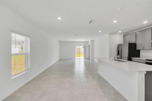 kitchen with gray cabinetry, stainless steel fridge with ice dispenser, sink, and light tile patterned floors