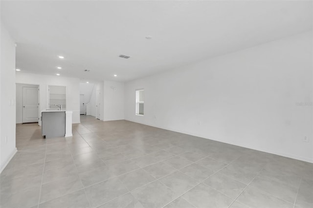 unfurnished living room featuring light tile patterned floors and sink