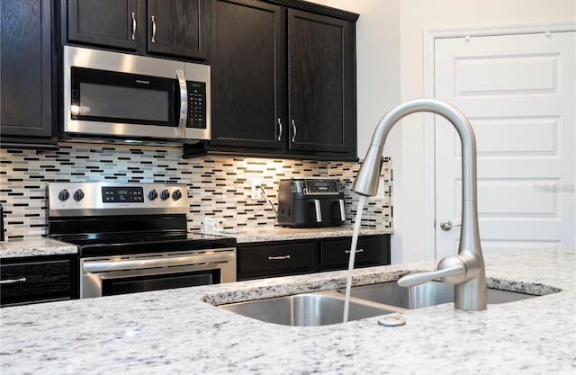 kitchen featuring light stone countertops, sink, appliances with stainless steel finishes, and backsplash