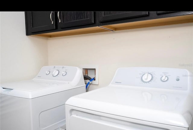 clothes washing area featuring independent washer and dryer and cabinets