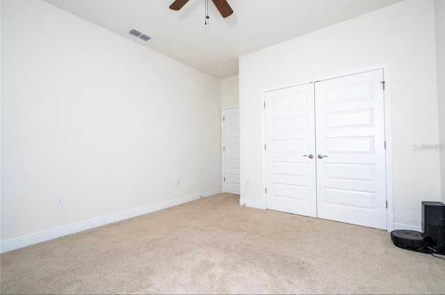 unfurnished bedroom with light carpet, a closet, and ceiling fan