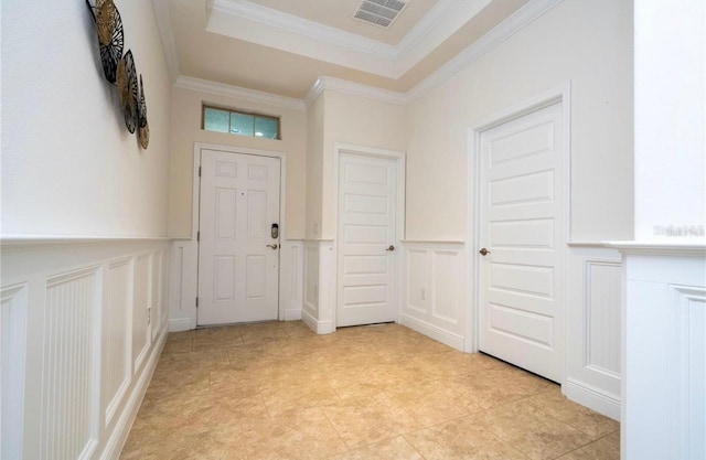 entryway with crown molding and a raised ceiling