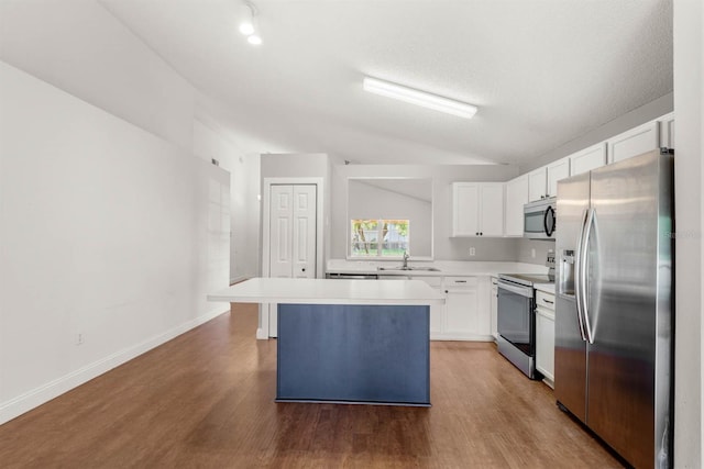 kitchen with white cabinets, a kitchen island, light wood-type flooring, vaulted ceiling, and stainless steel appliances