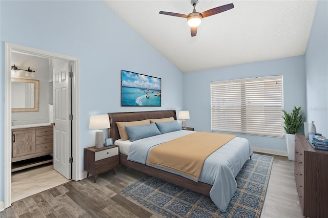 bedroom featuring light hardwood / wood-style floors, high vaulted ceiling, connected bathroom, and ceiling fan