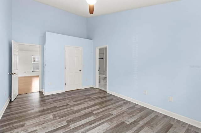 unfurnished bedroom featuring dark wood-type flooring, ceiling fan, and connected bathroom