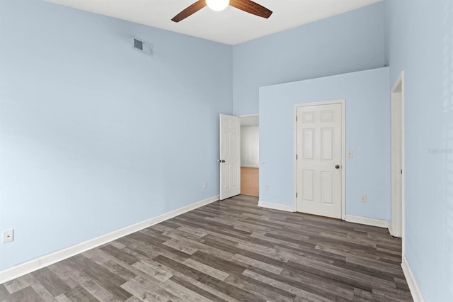 unfurnished bedroom featuring a high ceiling, dark hardwood / wood-style floors, and ceiling fan